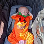 baby, infant, sleeping, pumpkin_costume, orange, stroller, baby_clothing, footwear, peaceful, cute, child, portrait, sunlight, resting, holiday, costume, baby_accessory, infant_clothing, baby_boy, baby_girl