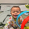 Veylin joined the competition — help win amazing prizes! baby, child, smiling, onesie, toy, bed, blanket, pillow, indoor, happy, playful, colorful, rings, infant, young_child, cute, face, sitting, person, room