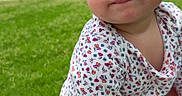Victoria is registered to the contest to win money with this photo: toddler, child, grass, outdoor, toy, smile, flower_pattern, pink_skirt, kneeling, person, face, cute, suburban, house, daylight, play, young_child, casual_clothing, nature, happy