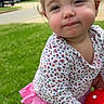Victoria is registered to the contest to win money with this photo: toddler, child, grass, outdoor, toy, smile, flower_pattern, pink_skirt, kneeling, person, face, cute, suburban, house, daylight, play, young_child, casual_clothing, nature, happy