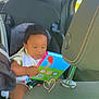 toddler, child, car_seat, book, vehicle_interior, seat, window, seatbelt, child_safety, toy, infant, car, reading, baby, casual, portrait, seat_headrest, clothing, seat_belt, heart_doodle