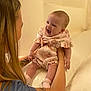 Heidi is registered to the contest to win money with this photo: baby, infant, smile, happy, woman, tattoo, arm, holding, pink_clothing, socks, indoor, couch, person, child, cute, joy, skin, face, expression, interaction