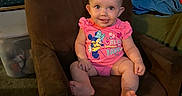 Letty joined the competition — help win amazing prizes! baby, child, armchair, pink_onesie, tongue_out, living_room, couch, clothing, diapers_box, carpet, furniture, person, smiling, cute, indoors, hair, face, seat, toy, colorful