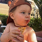 Ayden participe au concours pour gagner de l'argent avec cette photo : child, toddler, hat, food, chocolate, outdoor, garden, greenery, sunlight, skin, face, hands, summer, snack, cute, baby, necklace, playing, expression, casual