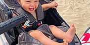 Ayden participe au concours pour gagner de l'argent avec cette photo : toddler, stroller, beach, sand, smiling, sunny, child, feet, pacifier, gray_fabric, outdoor, happy, playful, baby, vacation, summer, person, seat, relaxing, sunlight