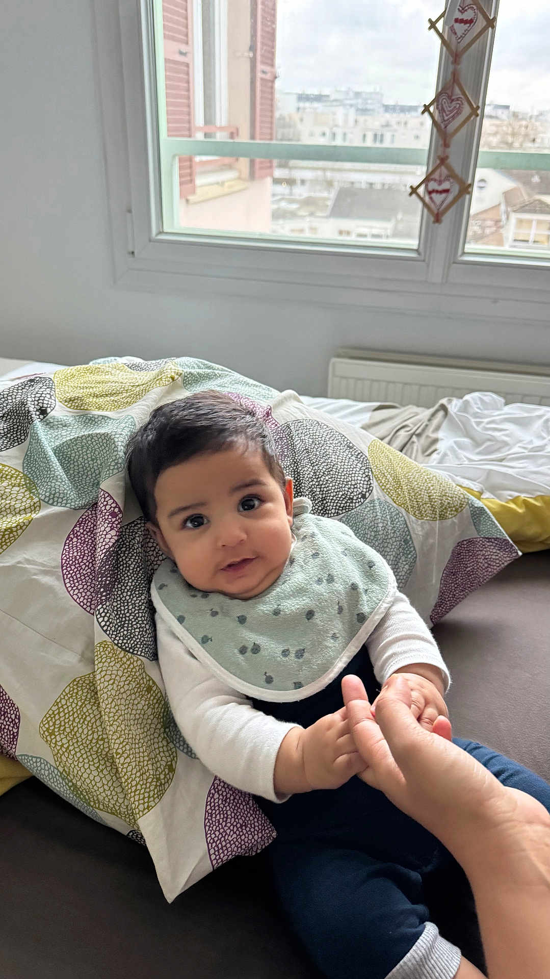Salman participe au concours pour gagner de l'argent avec cette photo : baby, child, infant, bed, blanket, window, hand, finger, person, indoor, clothing, bib, curly_hair, face, cute, smiling, sitting, cozy, home, natural_light
