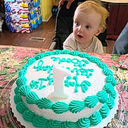 Bode Reed Jolly is registered to the contest to win money with this photo: baby, cake, birthday_cake, candle, high_chair, kitchen, child, icing, number_candle, table, curious, celebration, person, food, indoor, hand, frosting, plastic_container, decorated_cake, young_child