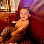 Jeremiah joined the competition — help win amazing prizes! baby, child, smiling, leather_couch, indoor, blanket, pants, happy, face, sitting, infant, home, natural_light, furniture, cozy, cute, portrait, relaxed, warm_colors, expression