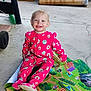 toddler, child, pajamas, pink_clothing, smiling, play_mat, colorful, indoor, concrete_floor, cardboard_boxes, cleaning_tool, happy, sitting, cute, person, young_child, casual, joyful, face, feet