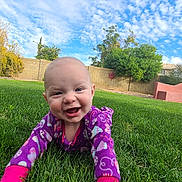 Rylee joined the competition — help win amazing prizes! baby, smiling, purple_onesie, grass, outdoor, crawling, happy, child, sky, clouds, greenery, tree, backyard, sunny, face, infant, nature, playful, cute, daytime