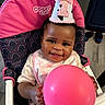 Haven is registered to the contest to win money with this photo: baby, balloon, birthday_hat, celebration, child, clothing, face, food_crumb, hand, happy, headwear, high_chair, indoor, infant, party, person, pink, seat, smile, toy