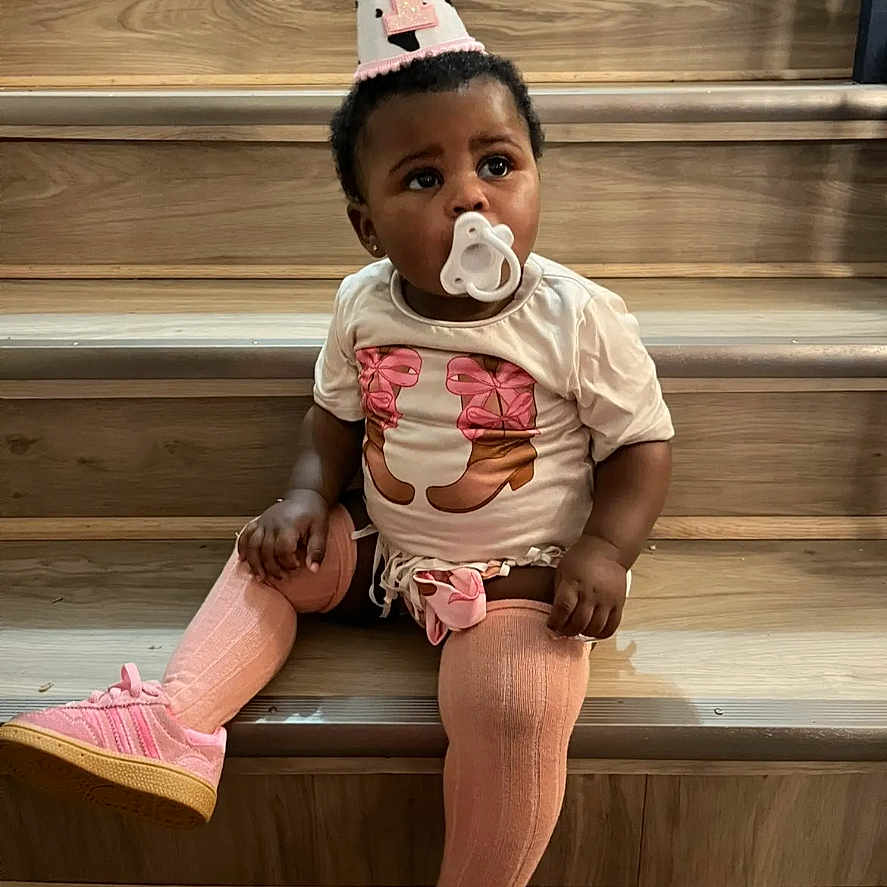 Haven is registered to the contest to win money with this photo: accessory, baby, casual_clothing, celebration, child, curious, cute, indoors, infant, one_child, pacifier, party_hat, pink_shoes, pink_tights, portrait, sitting, stairs, toddler, wooden_stairs, young_child