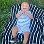 baby, infant, smiling, grass, outdoor, blanket, striped, shoes, footwear, happy, cute, child, nature, greenery, one_person, casual_clothing, summer, lying_down, playful, daylight