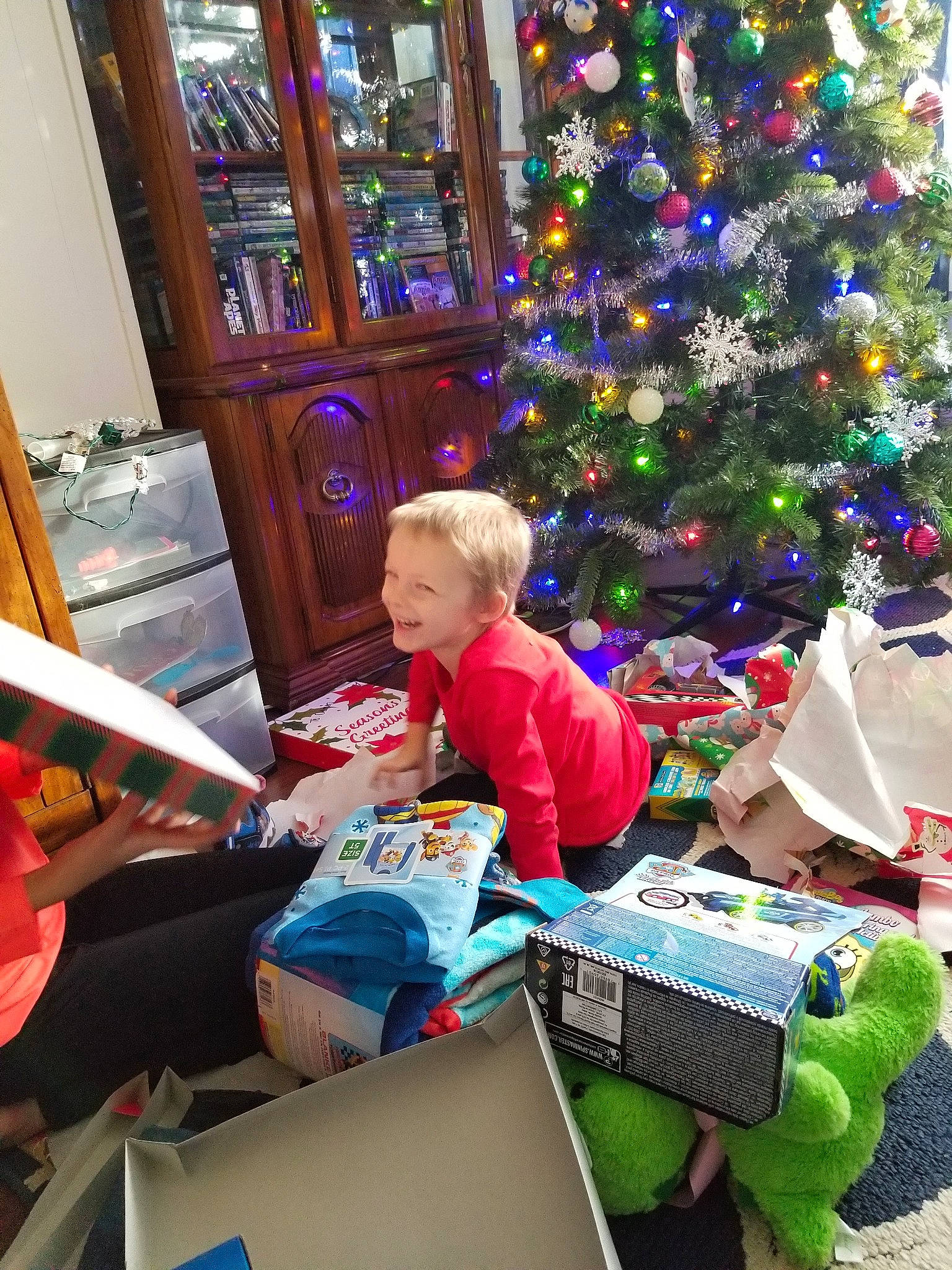 Damon is registered to the contest to win money with this photo: child, christmas, christmas_eve, christmas_ornament, christmas_tree, event, fun, holiday, home, interior_design, joy, person, plant, play, present, room, sitting, toddler, tree