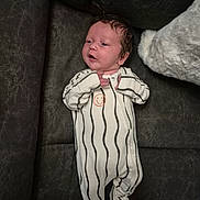 George joined the competition — help win amazing prizes! baby, infant, onesie, striped_clothing, smiley_face, couch, plush_toy, indoor, person, newborn, child, cute, soft_toy, furniture, relaxing, lying_down, young_child, small_hands, face, expression