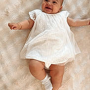 Mya participe au concours pour gagner de l'argent avec cette photo : baby, infant, smiling, white_dress, socks, lying_down, soft_blanket, cute, happy, child, portrait, one_person, indoor, skin, face, head, small_arms, small_legs, baby_girl, cozy