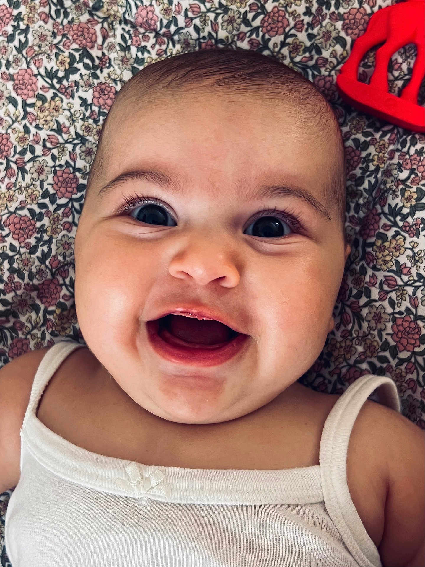 Mya a rejoint le concours — aidez-le/la à gagner de superbes lots ! baby, smiling, close_up, face, infant, happy, child, white_clothing, blanket, pattern, toy, red_toy, lying_down, portrait, cute, cheerful, skin, head, eyes, mouth