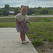 Clairann is registered to the contest to win money with this photo: casual_clothing, child, cloudy_sky, daytime, dress, grass, greenery, happy, nature, outdoor, person, pigtails, playful, sidewalk, small_toy, smiling, toddler, toy, white_shoes, young_child