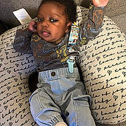 Aiden joined the competition — help win amazing prizes! baby, infant, child, cushion, clothing, denim, sock, face, person, cute, indoor, fabric, pattern, text, comfort, relaxing, raising_hand, smiling, black_hair, casual