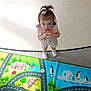 toddler, child, indoor, play_mat, colorful, toy, clothing, socks, animal_illustrations, panda, penguin, dolphin, koalas, rhino, road_pattern, person, looking_up, hair_bow, curious, floor