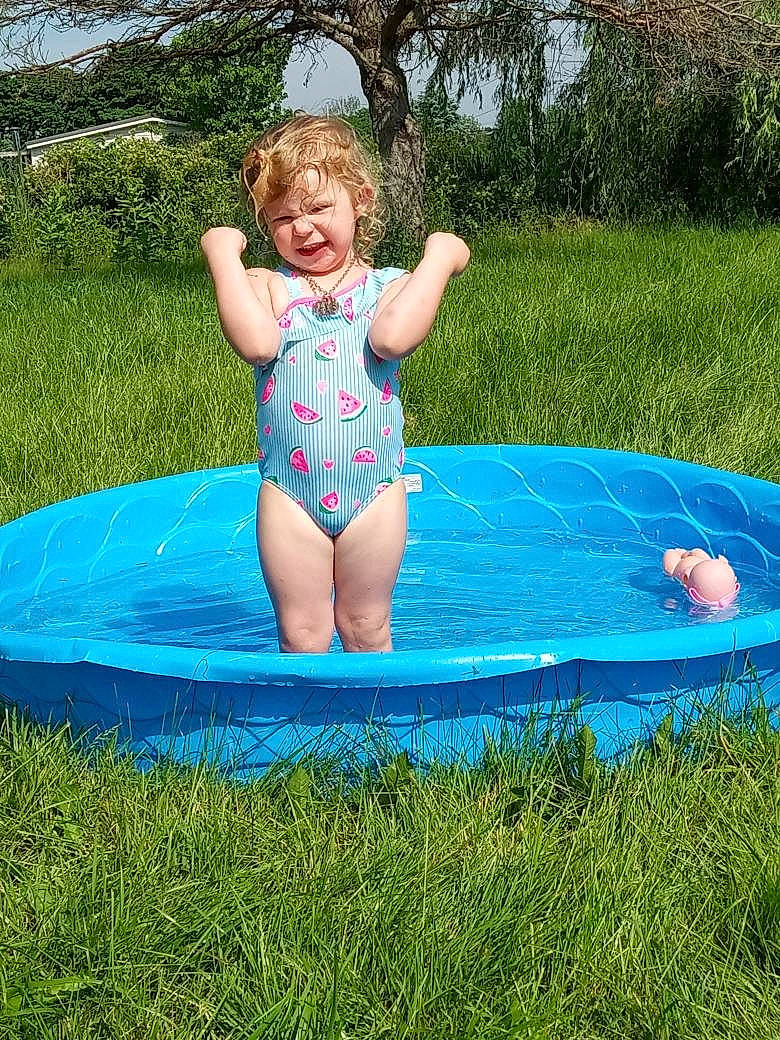 Arielle is registered to the contest to win money with this photo: aqua, baby_toddler_clothing, barefoot, electric_blue, fun, grass, happy, inflatable, lawn, leisure, meadow, people_in_nature, person, plant, play, recreation, smile, swimwear, toddler, tree
