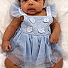baby, infant, blue_dress, headband, cute, lying_down, blanket, soft_texture, chubby_cheeks, curious_eyes, portrait, child, adorable, newborn, small_hands, small_feet, indoors, closeup, fashion, smiling