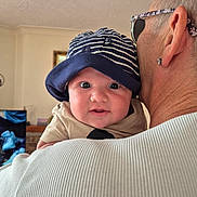 Dylan joined the competition — help win amazing prizes! baby, hat, striped, person, face, indoor, glasses, shoulder, curious, closeup, child, adult, holding, portrait, expression, headwear, casual, light, skin, eyewear