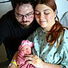 newborn, baby, mother, father, hospital, hospital_gown, family, love, affection, parenthood, medical_poster, bed, blanket, headband, indoor, person, holding, tenderness, happy, portrait