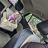 backseat, car, car_interior, dog, fluffy_bed, headrest, lying_down, outdoor_view, pet_bed, pink_harness, portrait, puppy, road_trip, seatbelt, seated, small_dog, trees, vehicle, white_dog, window