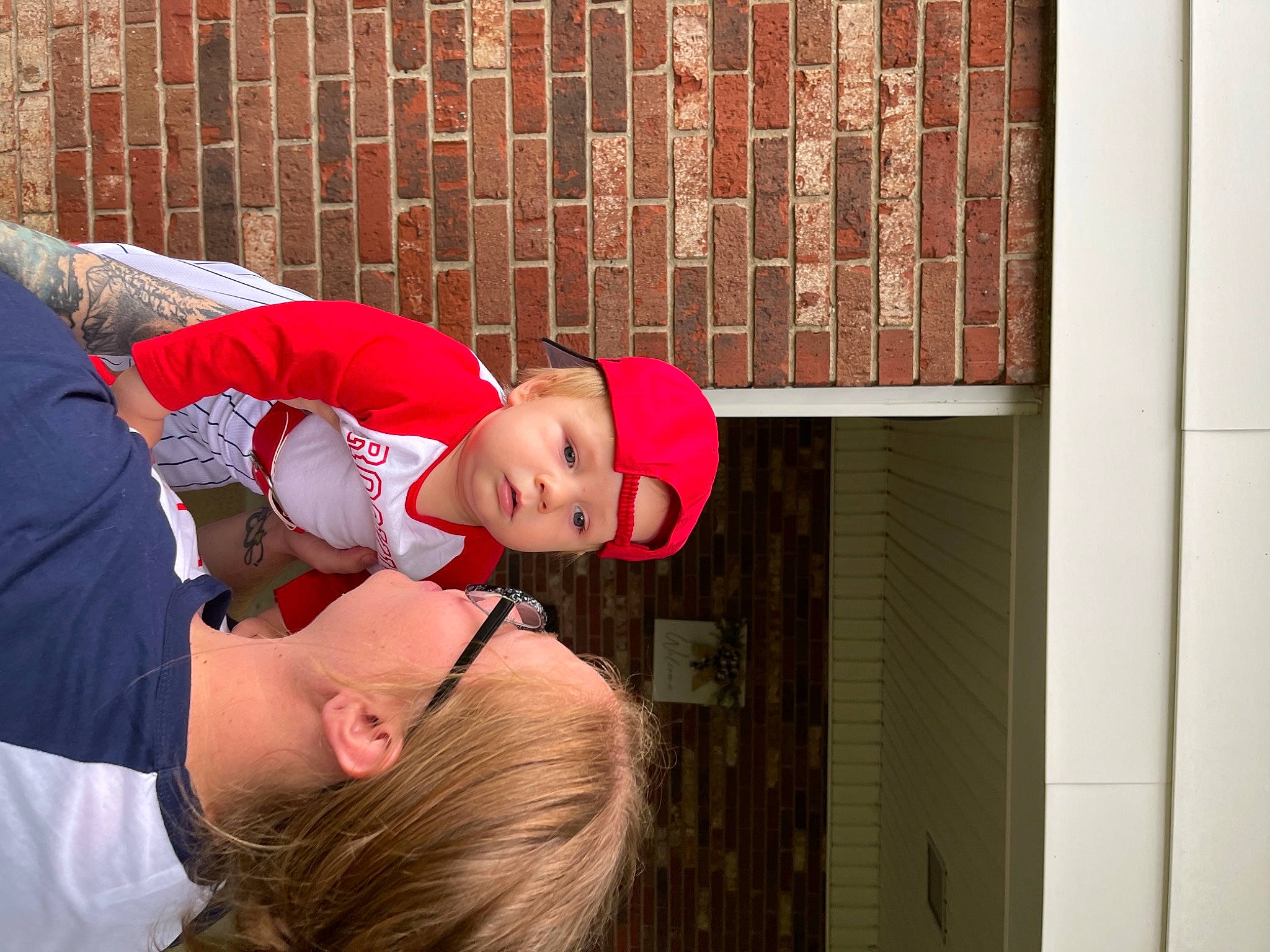 Van is registered to the contest to win money with this photo: brick, cap, carmine, elbow, event, eyewear, flesh, fun, happy, headwear, human_leg, leisure, magenta, orange, person, room, sitting, t_shirt, thigh, tree