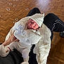 baby, sleeping, knitwear, white, hat, mittens, blanket, lap, person, bubbles, floor, wooden_floor, cozy, peaceful, indoor, hands, footwear, black_pants, soft_light, portrait