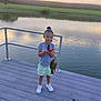 activity, child, clothing, dock, fish, fishing_rod, grass, happy, lake, leisure, nature, outdoor, person, reflection, shoes, sky, summer, sunset, tree, water