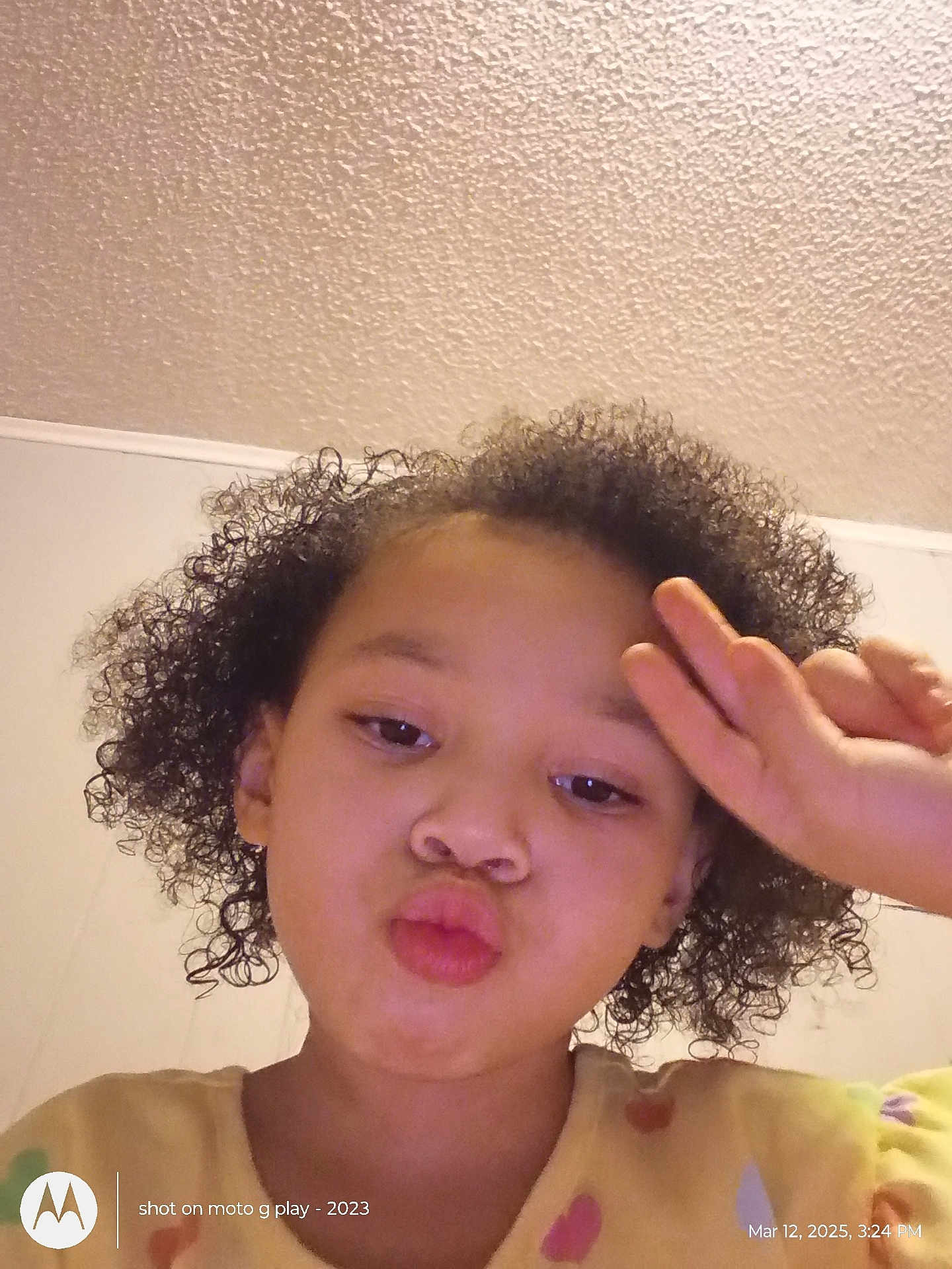 Kai'Lani Garnett joined the competition — help win amazing prizes! child, curly_hair, indoor, peace_sign, yellow_clothing, heart_pattern, face, portrait, selfie, playful, expression, person, casual, young, cute, smile, hand_gesture, wall, ceiling, texture