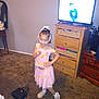 Kai'Lani Garnett is registered to the contest to win money with this photo: carpet, child, decor, dresser, floor, floral_pattern, furniture, girl, hair_bow, handbag, home_interior, living_room, mirror, necklace, pink_dress, portrait, posing, slippers, smiling, television