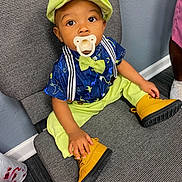 Zayven is registered to the contest to win money with this photo: child, toddler, hat, bow_tie, pacifier, shirt, pants, boots, chair, sitting, indoor, dinosaur_print, suspenders, curious, cute, baby, footwear, fashion, colorful, portrait