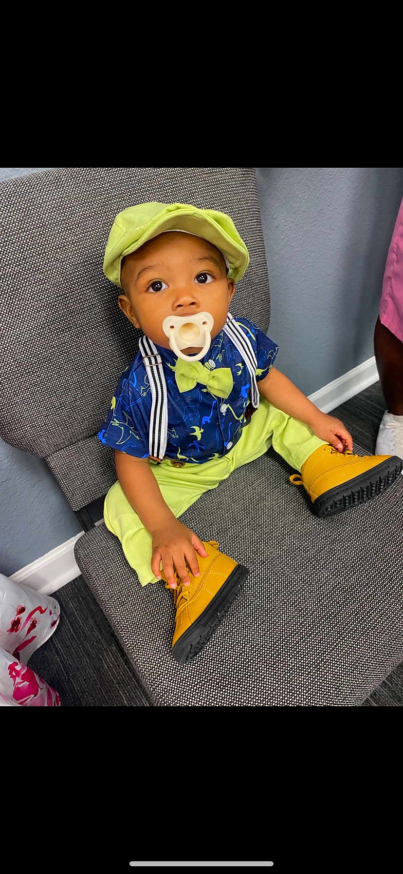 Zayven is registered to the contest to win money with this photo: child, toddler, hat, bow_tie, pacifier, shirt, pants, boots, chair, sitting, indoor, dinosaur_print, suspenders, curious, cute, baby, footwear, fashion, colorful, portrait