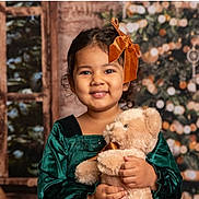 Anya joined the competition — help win amazing prizes! child, girl, teddy_bear, green_dress, orange_bow, smile, portrait, holiday, christmas_tree, decorations, plush_toy, indoor, window, cozy, festive, cute, happy, celebration, childhood, warmth