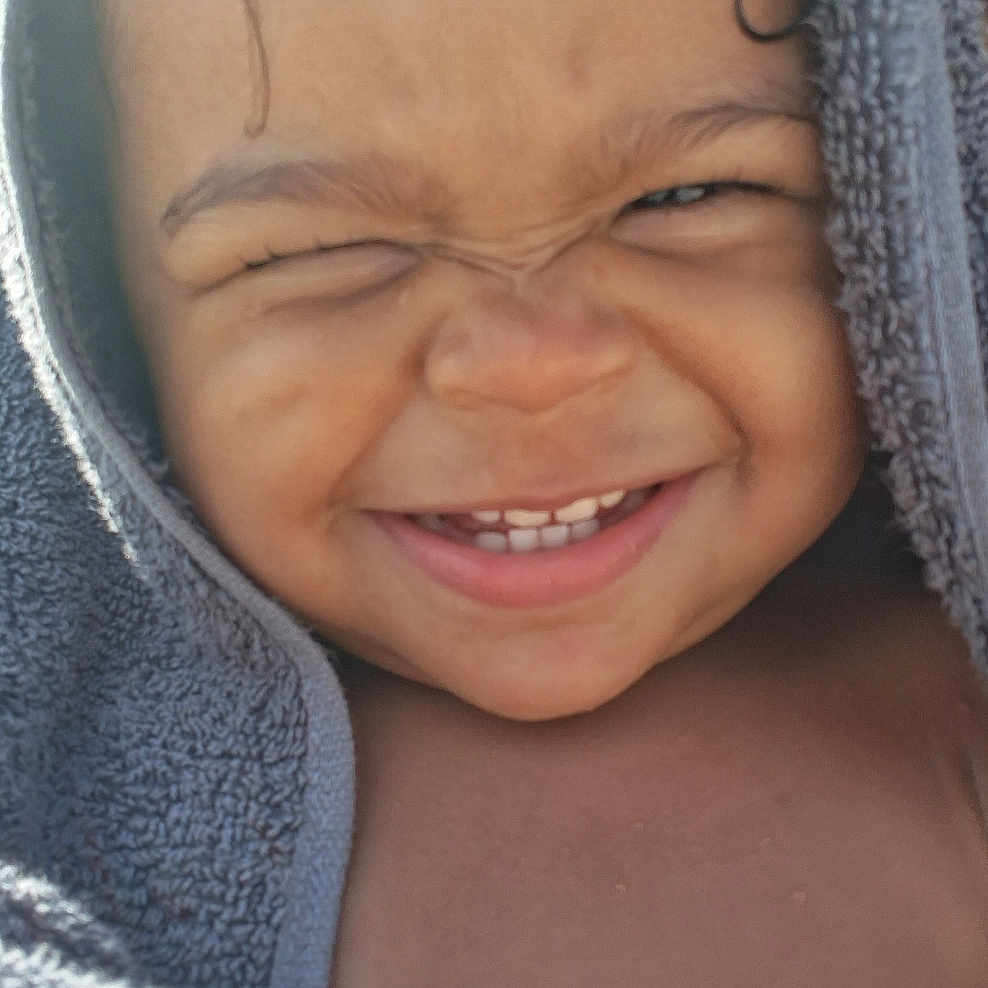 Xyliah is registered to the contest to win money with this photo: baby, child, closeup, cute, expression, face, hand, happy, joy, outdoor, person, portrait, skin, smile, sunlight, teeth, toddler, towel, warm, wet_hair