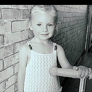 Jahnaë a rejoint le concours — aidez-le/la à gagner de superbes lots ! child, girl, scooter, brick_wall, portrait, indoor, smile, blonde_hair, knitted_top, playful, young, handle, person, cute, standing, looking_at_camera, monochrome, photography, innocence, bright_eyes