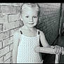 child, girl, scooter, brick_wall, portrait, indoor, smile, blonde_hair, knitted_top, playful, young, handle, person, cute, standing, looking_at_camera, monochrome, photography, innocence, bright_eyes