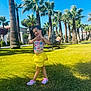 child, girl, smiling, playful, yellow_skirt, colorful_top, palm_trees, grass, sunny, outdoor, blue_sky, hanging_chair, boy, vacation, summer, happy, nature, park, leisure, fun
