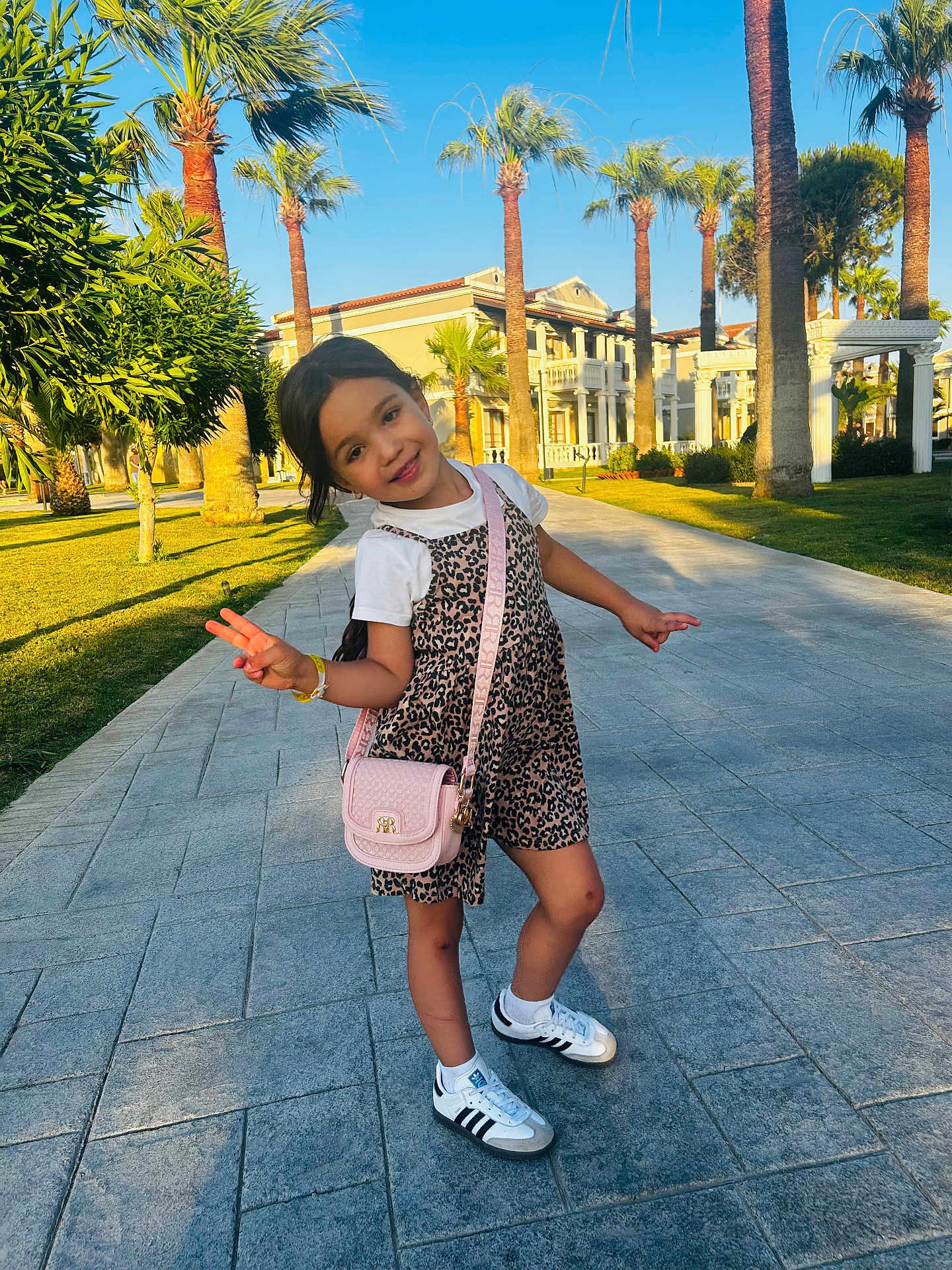 Eva joined the competition — help win amazing prizes! child, girl, smiling, pose, peace_sign, leopard_print, dress, white_tshirt, sneakers, pink_purse, sidewalk, palm_trees, sunny, outdoor, building, greenery, happy, summer, fashion, playful