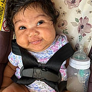 Gianni joined the competition — help win amazing prizes! baby, infant, car_seat, bottle, milk, smile, face, hair, clothing, floral_pattern, seat_belt, child, cute, expression, indoors, person, skin, closeup, feeding, sitting