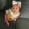 baby, infant, child, bow, headwear, couch, upholstery, clothing, sitting, indoors, looking_up, cute, young, person, skin, face, expression, bright_colors, texture, comfortable