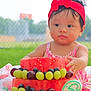 Lydia joined the competition — help win amazing prizes! baby, child, watermelon, fruit, grapes, blueberries, headband, red, dress, outdoor, grass, blanket, birthday, cake, summer, cute, food, table, celebration, playful