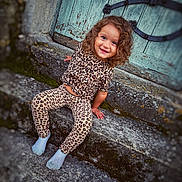 Kaila a rejoint le concours — aidez-le/la à gagner de superbes lots ! candid, casual, child, clothing, curly_hair, cute, door, happy, leopard_print, moss, outdoor, person, portrait, rustic, sitting, smile, socks, stone_steps, toddler, young_child