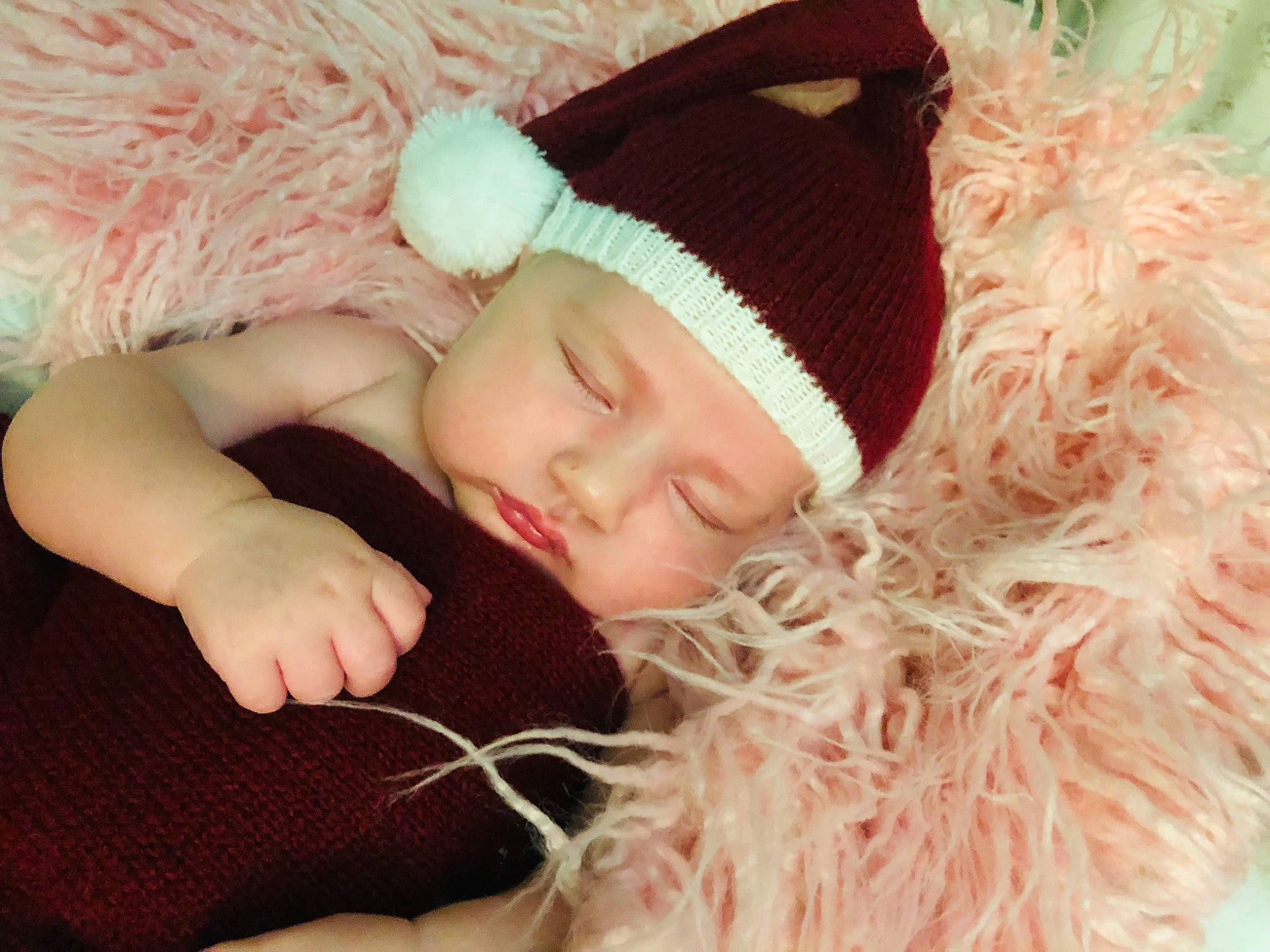 Emilee is registered to the contest to win money with this photo: baby, baby_sleeping, brown_hair, cap, child, comfort, costume_hat, eyelash, fashion_accessory, fur, grass, hair_accessory, headband, headgear, headpiece, headwear, knit_cap, linens, person, pink