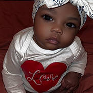 Fayonah joined the competition — help win amazing prizes! baby, infant, child, headband, bow, onesie, love, heart, clothing, skin, hand, face, eyes, sitting, blanket, indoors, cute, portrait, soft, expression