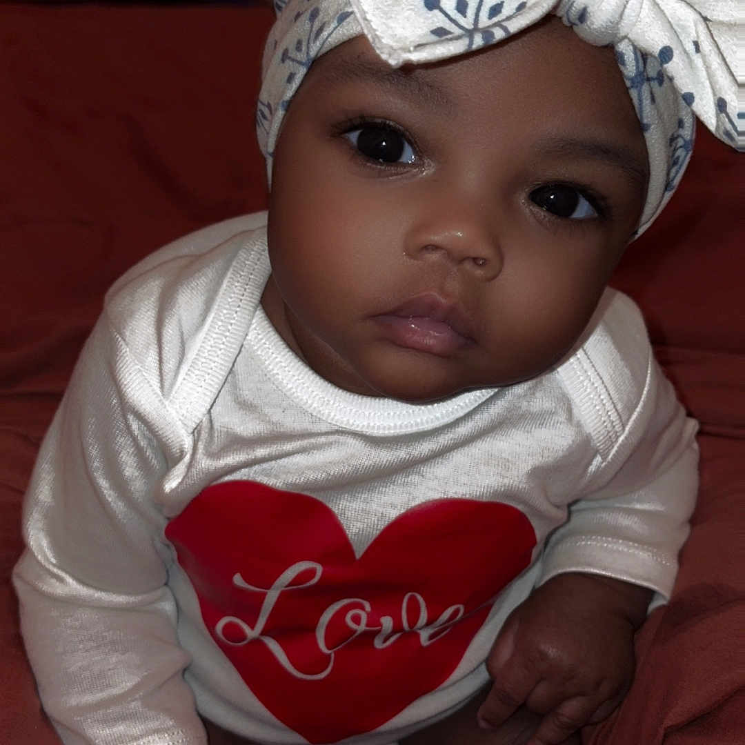 Fayonah joined the competition — help win amazing prizes! baby, blanket, bow, child, clothing, cute, expression, eyes, face, hand, headband, heart, indoors, infant, love, onesie, portrait, sitting, skin, soft