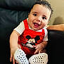 baby, child, smiling, red_clothing, mickey_mouse, white_socks, black_chair, happy, cute, indoors, portrait, sitting, short_hair, infant, playful, casual_clothing, closeup, person, fun, bright